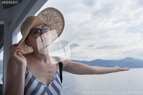 Image of Disappointed female tourist on summer cruss ship vacation, checking if it rains, looking angry at overcast cloudy sky. Allways take the weather with you on summer vacations