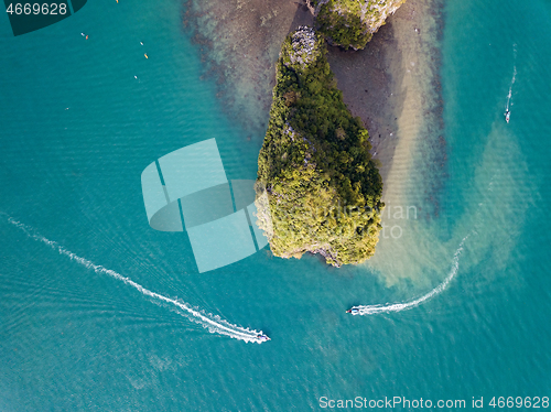 Image of two boats go around a rocky island