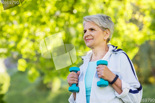 Image of senior woman with dumbbells exercising at park