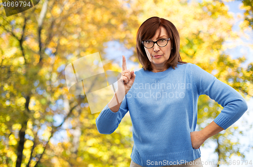 Image of displeased senior woman in glasses warning