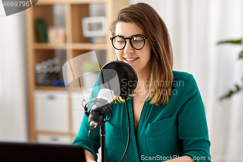 Image of woman with microphone recording podcast at studio