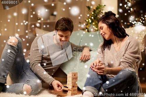 Image of happy couple playing block-stacking game at home