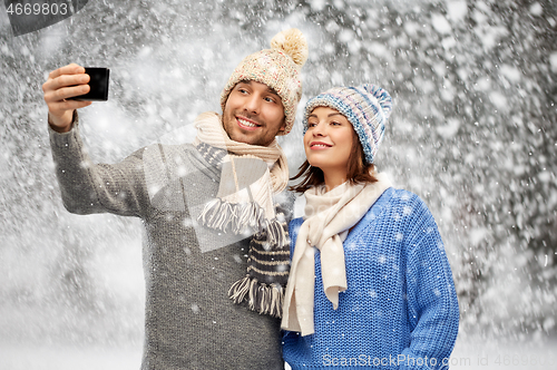 Image of couple in winter hats taking selfie by smartphone