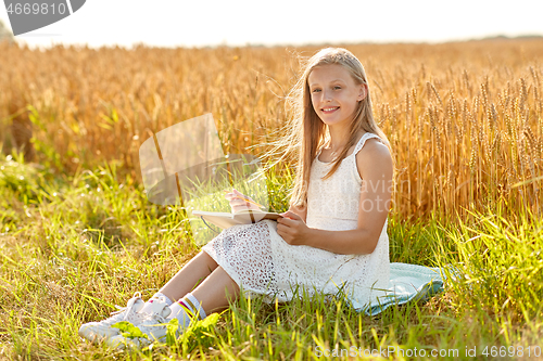 Image of smiling girl writing to diary on cereal field