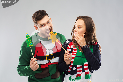 Image of couple with christmas party props in ugly sweaters