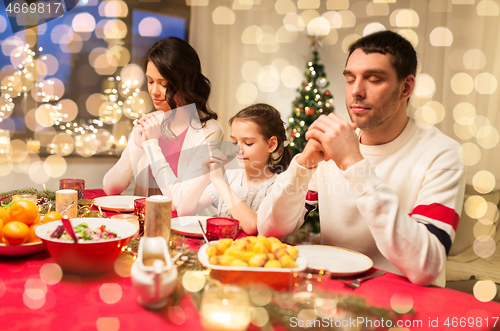 Image of family praying before meal at christmas dinner