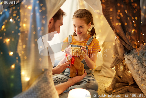 Image of happy family playing with toy in kids tent at home