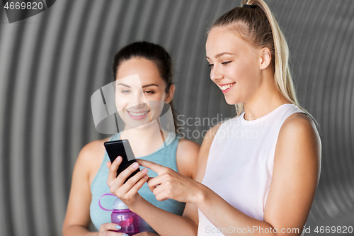 Image of women or female friends with smartphone and flask