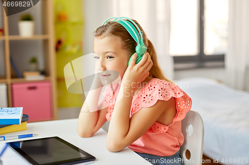 Image of girl in headphones with tablet computer at home