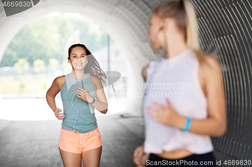 Image of women or female friends with earphones running