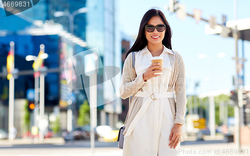 Image of smiling woman with takeaway coffee cup in city