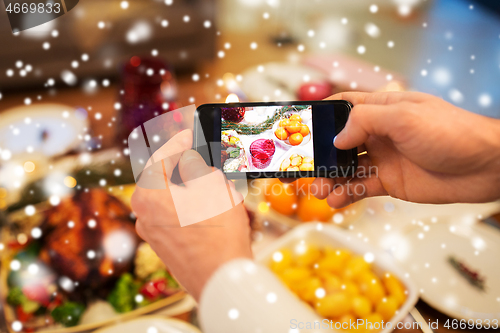 Image of hands photographing food at christmas dinner