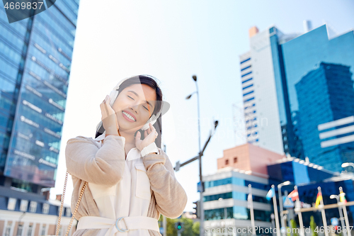 Image of happy smiling asian woman with headphones in city