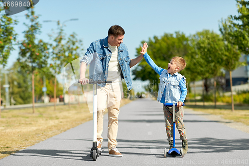 Image of father and son with scooters making high five