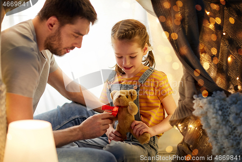 Image of happy family playing with toy in kids tent at home