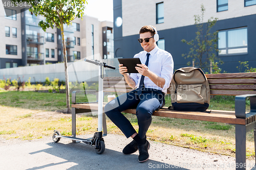 Image of businessman with tablet pc, headphones and scooter