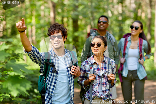 Image of group of friends with backpacks hiking in forest