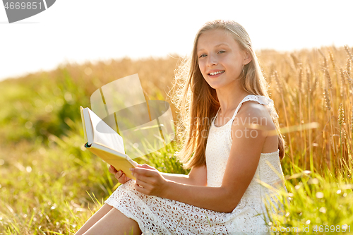 Image of smiling young girl reading book on cereal field