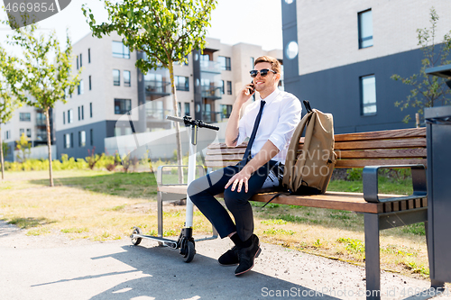 Image of businessman with scooter calling on smartphone