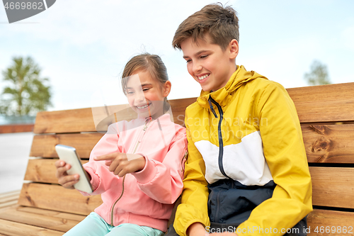 Image of children with smartphones sitting on street bench