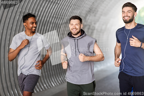 Image of male friends with earphones running outdoors