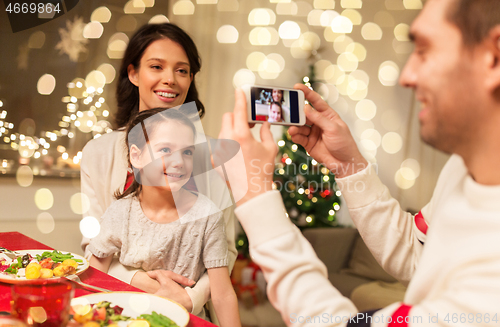 Image of happy family taking picture at christmas dinner