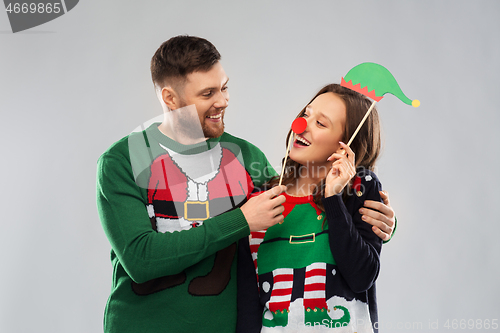 Image of couple with christmas party props in ugly sweaters