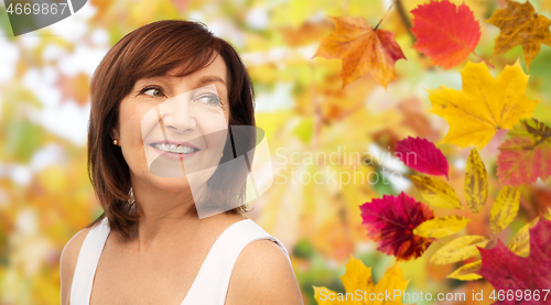 Image of portrait of happy senior woman over autumn leaves