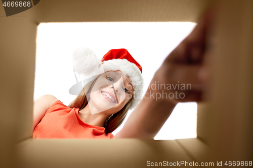 Image of girl in santa hat taking christmas gift out of box