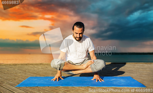 Image of man making yoga in scale pose outdoors