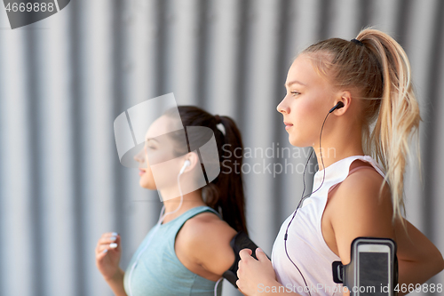 Image of young women with earphones and smartphones running