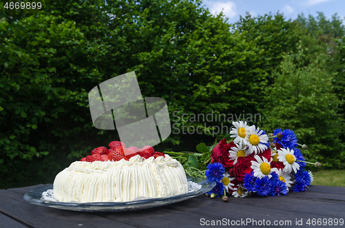 Image of Cream cake and summer flowers in a garden