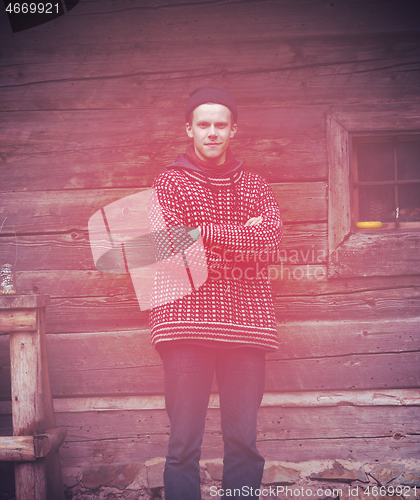 Image of young hipster in front of wooden house