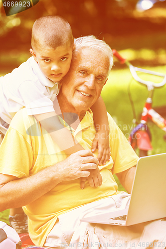 Image of grandfather and child using laptop