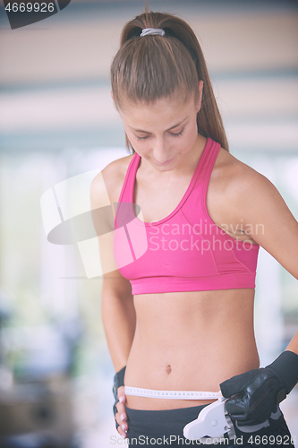 Image of young fit woman measuring belly