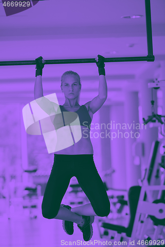 Image of young woman in fitness gym lifting on bar