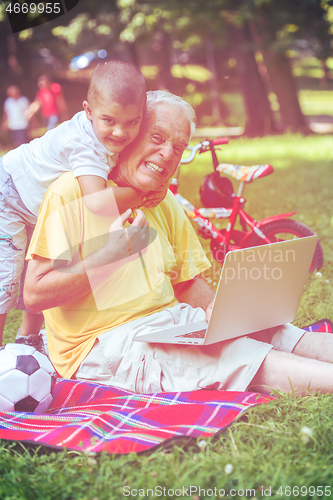 Image of grandfather and child using laptop