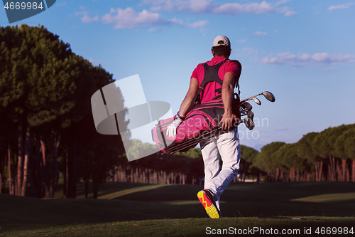 Image of golfer  walking and carrying golf  bag