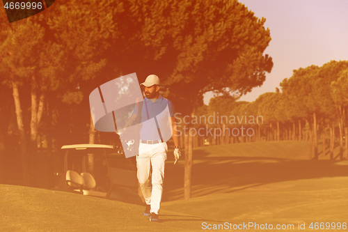 Image of golfer  walking and carrying golf  bag