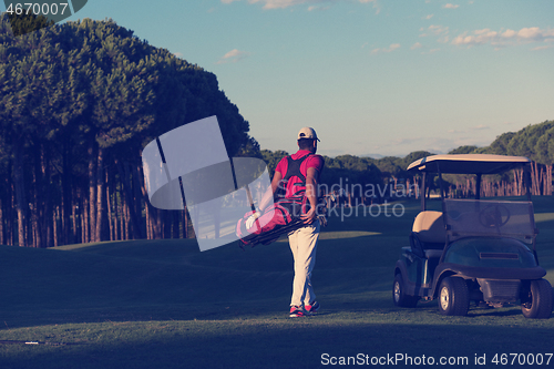 Image of golfer  walking and carrying golf  bag