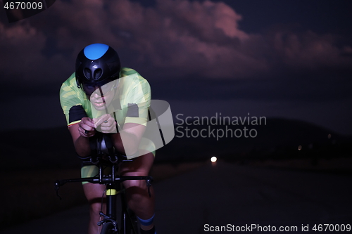 Image of triathlon athlete riding bike fast at night