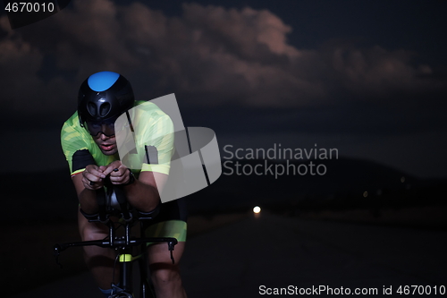 Image of triathlon athlete riding bike fast at night