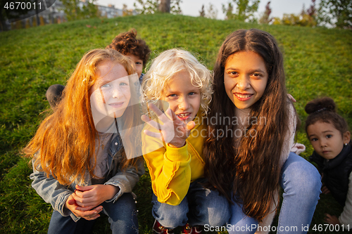 Image of Interracial group of kids, girls and boys playing together at the park in summer day