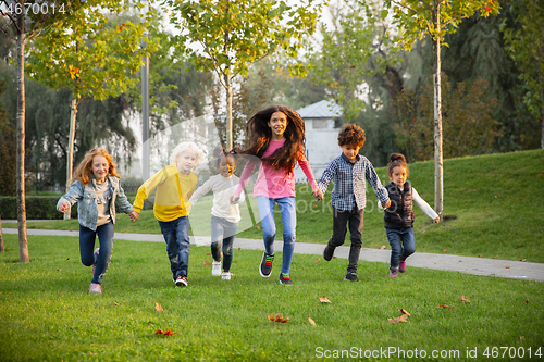 Image of Interracial group of kids, girls and boys playing together at the park in summer day