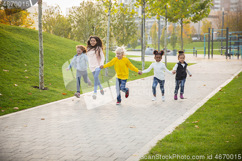 Image of Interracial group of kids, girls and boys playing together at the park in summer day