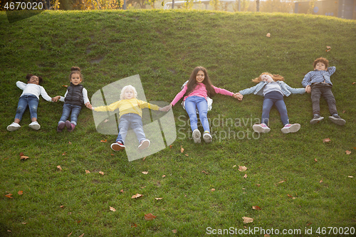 Image of Interracial group of kids, girls and boys playing together at the park in summer day