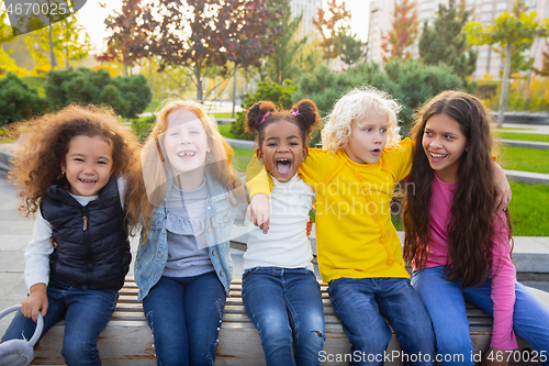 Image of Interracial group of kids, girls and boys playing together at the park in summer day