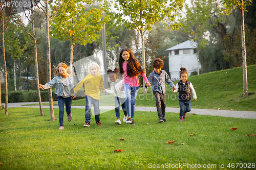 Image of Interracial group of kids, girls and boys playing together at the park in summer day