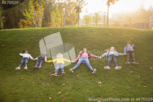 Image of Interracial group of kids, girls and boys playing together at the park in summer day