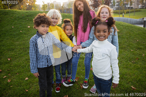 Image of Interracial group of kids, girls and boys playing together at the park in summer day